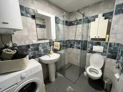 a bathroom with a toilet and a sink and a washing machine at Apartman Green in Vrnjačka Banja