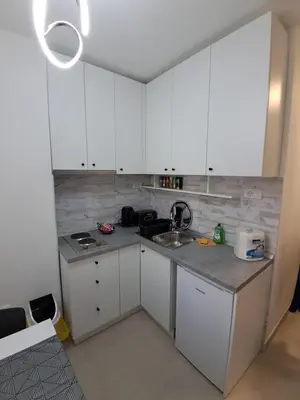 a kitchen with white cabinets and a sink at Zenit apartmani in Niš