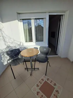 a table and chairs in a room with a window at Zenit apartmani in Niš