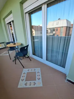 a balcony with a table and chairs and a large window at Zenit apartmani in Niš