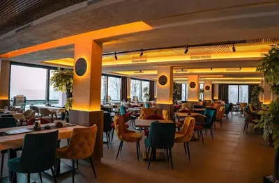 a restaurant with many tables and chairs and windows at Nlux 30 MamaBaba Resort&Spa in Kopaonik