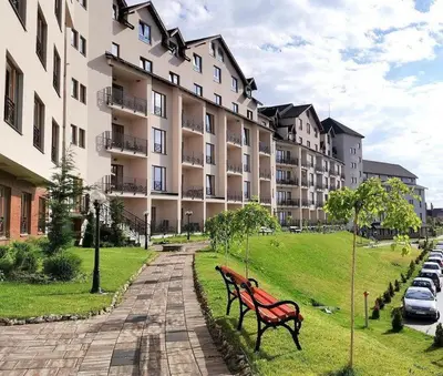 two park benches in front of a large building at Nlux 30 MamaBaba Resort&Spa in Kopaonik