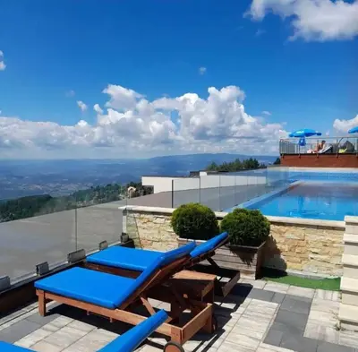 a swimming pool with blue lounge chairs on a patio at Nlux 30 MamaBaba Resort&Spa in Kopaonik