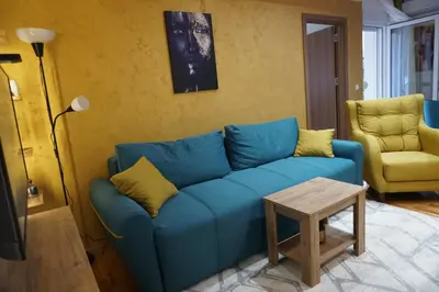 a living room with a blue couch and a table at Apartman Petar i Dunja in Vranje