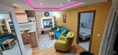 a living room with a blue couch and a bedroom at Apartman Petar i Dunja in Vranje