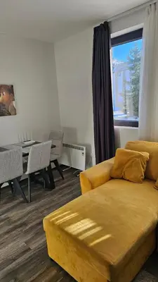 a living room with a yellow couch and a table at Sunčani Breg app 8 in Kopaonik