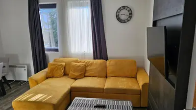 a living room with a couch and a clock on the wall at Sunčani Breg app 8 in Kopaonik