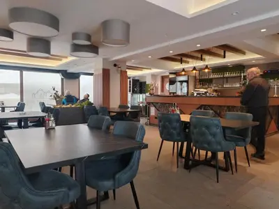 a man standing in a restaurant with tables and chairs at Apartman Alastra AP 02 President Kop in Kopaonik