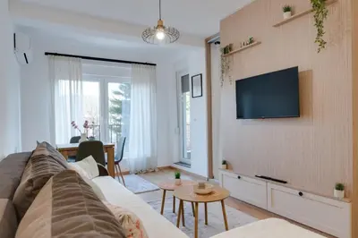 a living room with a couch and a tv on a wall at Apartman Svitanje Vrnjacka banja in Vrnjačka Banja