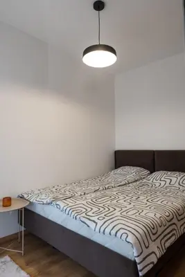 a bed in a room with a white wall at Apartman Svitanje Vrnjacka banja in Vrnjačka Banja