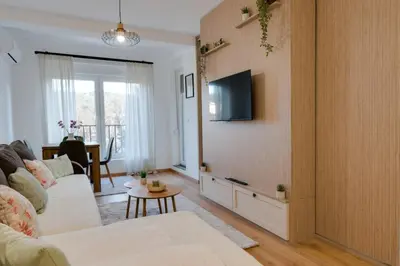 a living room with a couch and a tv on a wall at Apartman Svitanje Vrnjacka banja in Vrnjačka Banja
