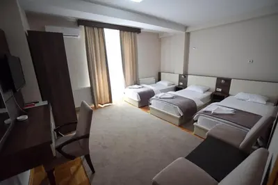 a hotel room with three beds and a flat screen tv at Garni Uni Elita Lux Hotel in Niš