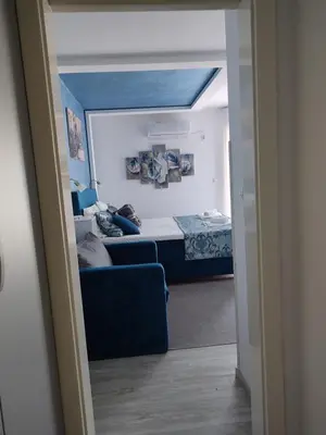 a bedroom with a bed and a blue couch at Apartman Plava nota in Vrnjačka Banja