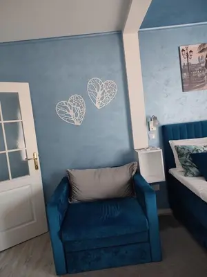 a room with a blue couch and two hearts on the wall at Apartman Plava nota in Vrnjačka Banja