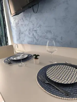 two plates and wine glasses sitting on a table at Apartman Plava nota in Vrnjačka Banja