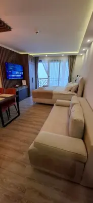a living room with three couches and a television at Deluxe Mountain View Studio ViS in Residence Hill Hotel Kopaonik in Kopaonik