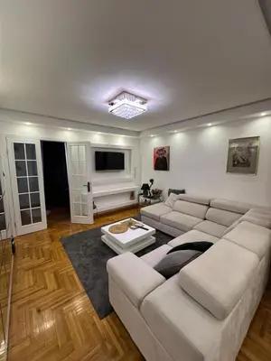 a living room with a white couch and a tv at Aurora Nis in Niš
