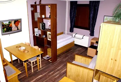 a small room with a bed and a table and chair at Vila Nikola 202 centar in Kopaonik