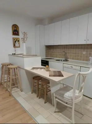 a kitchen with white cabinets and a table and chairs at Nektar 88 Lux in Vrnjačka Banja