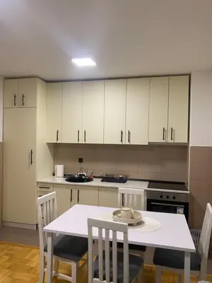 a kitchen with white cabinets and a table and chairs at Apartman Filip2 in Kruševac