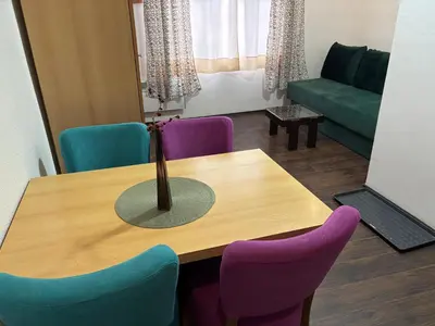 a room with a table with chairs and a couch at Apartments Ozren in Soko Banja