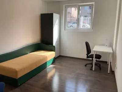 a bedroom with a bed and a desk and a window at Sudent Rooms in Niš