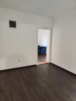an empty room with white walls and wood floors at Sudent Rooms in Niš