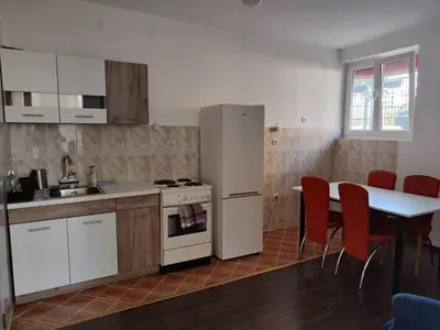 a kitchen with a white refrigerator and a table with red chairs at Sudent Rooms in Niš