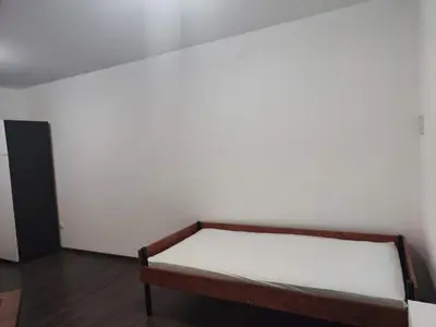 a bed in a room with a white wall at Sudent Rooms in Niš