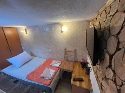 a bedroom with a bed and a table and a stone wall at Vlasinska Bajka in Vlasina Rid