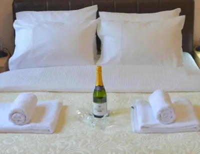 a bottle of wine sitting on top of a bed at Apolon Spa Lux in Vrnjačka Banja