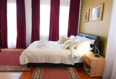 a hotel room with a bed with white sheets and pillows at Apolon Spa Lux in Vrnjačka Banja