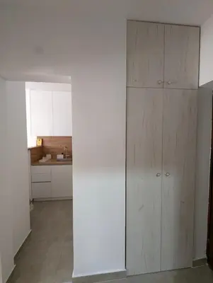a kitchen with white cabinets and a large wooden cabinet at Apartman Karingtonka free parking in Vranje