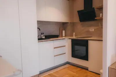 a kitchen with white cabinets and a black dishwasher at Apartman Mina - Vrnjačka Banja in Vrnjačka Banja