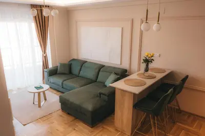 a living room with a green couch and a table at Apartman Mina - Vrnjačka Banja in Vrnjačka Banja