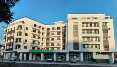 a large building with cars parked in front of it at Apartman Mina - Vrnjačka Banja in Vrnjačka Banja