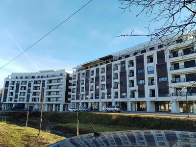 a large white building with cars parked in front of it at Apartman Mina - Vrnjačka Banja in Vrnjačka Banja