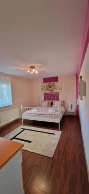 a bedroom with a white bed and a wooden floor at Plavi Dom in Ćuprija