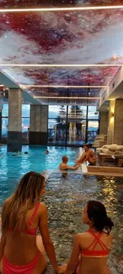 two women sitting in the swimming pool at a hotel at Residence Hill apartment TammyMatty in Kopaonik