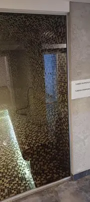 a bathroom with a glass shower with brown tiles at Residence Hill apartment TammyMatty in Kopaonik
