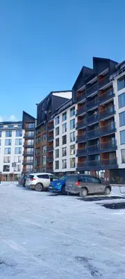 a parking lot with cars parked in front of a building at Residence Hill apartment TammyMatty in Kopaonik
