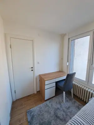 a bedroom with a desk and a chair and a window at Apartman Tea in Niš