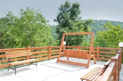 two benches on a deck with trees in the background at Serbina in Kandalica