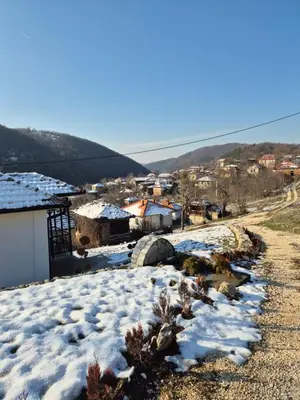 a village with snow on the ground next to a building at Serbina in Kandalica