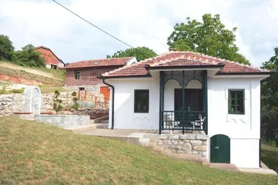 a small white house with a stone wall at Serbina in Kandalica