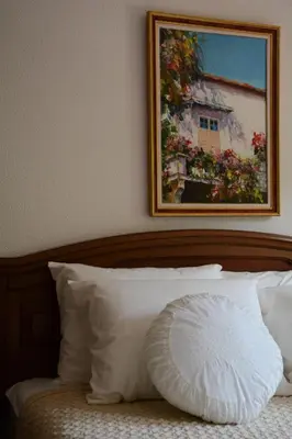 a pillow sitting on a bed with a picture on the wall at Serbina in Kandalica