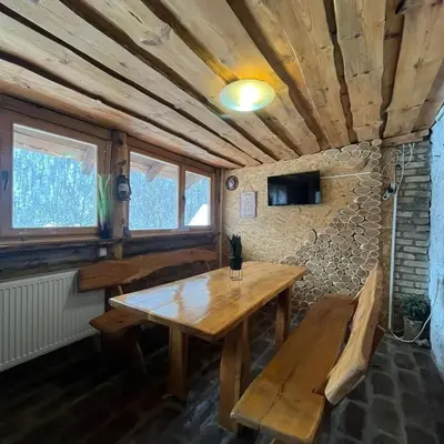 a dining room with a wooden table and a bench at Apartmani Manojlović in Crni Vrh
