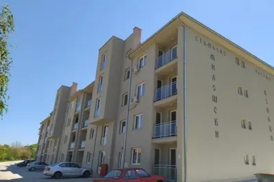 a large building with cars parked in a parking lot at Apartman-studio Sokobanja in Soko Banja