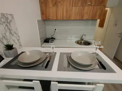 a kitchen with a table with plates and wine glasses at Apartman-studio Sokobanja in Soko Banja