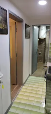 a hallway of a bathroom with a shower and a door at Apartman Aki in Niš